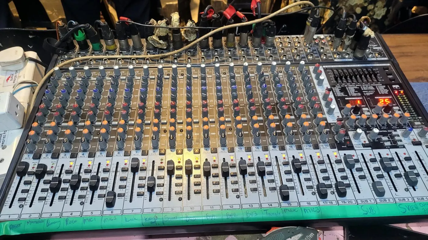 Large live mixing desk with rows of faders and knobs