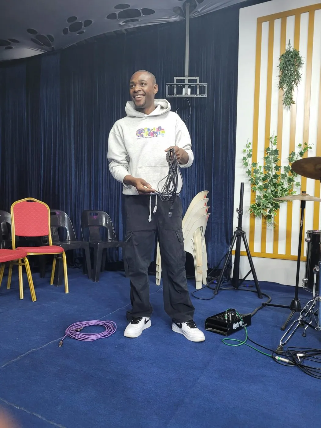 Alpha setting up a PA speaker on a stand at a venue